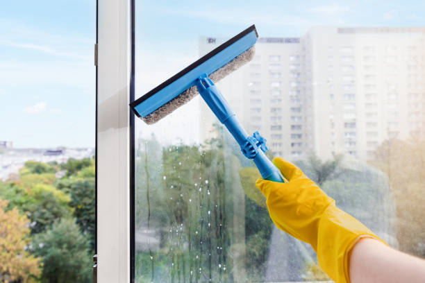 Hand In Yellow Glove Cleaning Window With Squeegee