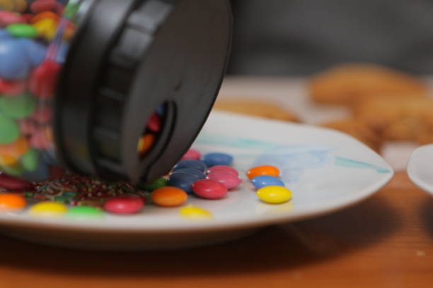 Colorful chocolate buttons spilling from a jar onto a plate, creating a sweet and tempting treat