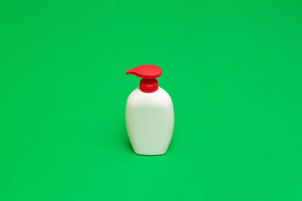 White plastic dispenser bottle with red pump on a vibrant green background, ideal for showcasing liquid soap, shampoo, or lotion products