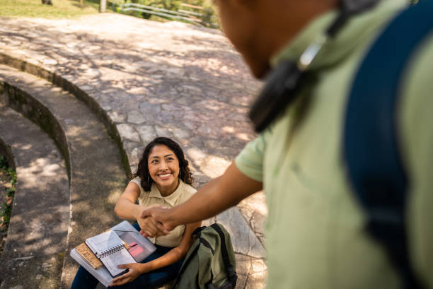 Young woman student greeting friend in a public park