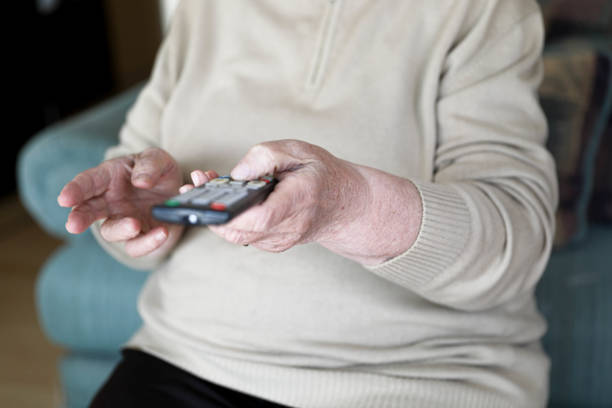 istock An Old Hand Holding a TV Remote 2201486033