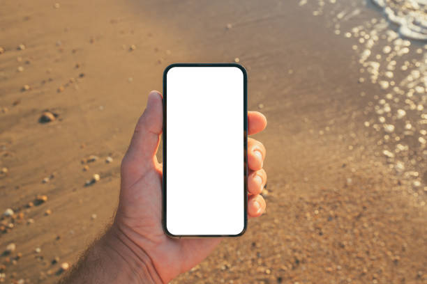 istock Smartphone mockup at seaside, man using mobile phone on sandy beach 2201490261