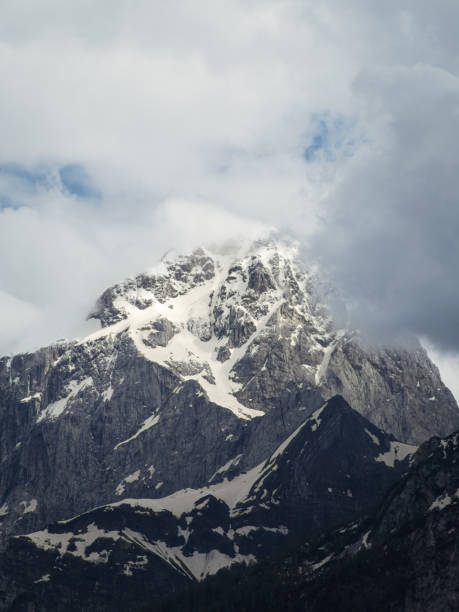 istock Dramatic snow-capped mountain peak shrouded in clouds 2201496789