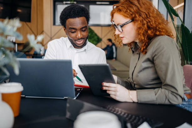 istock Two young adults working together in office while sitting in front of laptop and tablet 2201500809