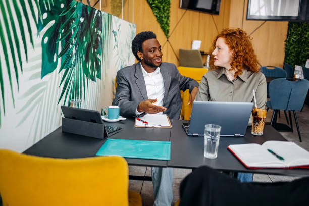istock Two young adults working together in office while sitting in front of laptop 2201500997