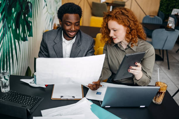istock Two young adults working together in office while sitting in front of laptop and digital tablet 2201501046
