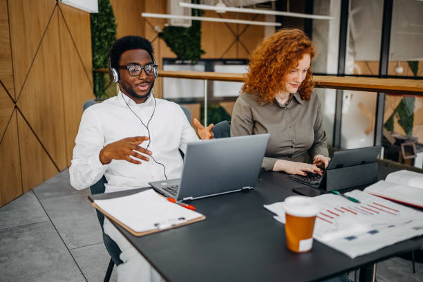 istock Two young adults working together in office while one is having a online meeting 2201501127
