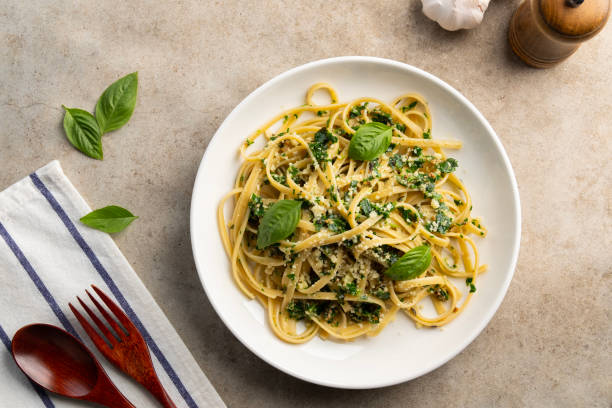 istock fettuccine pasta with kale walnut pesto sauce in white plate. 2201507815
