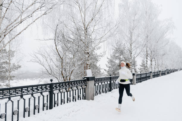istock young caucasian woman runs in park in winter 2201511373