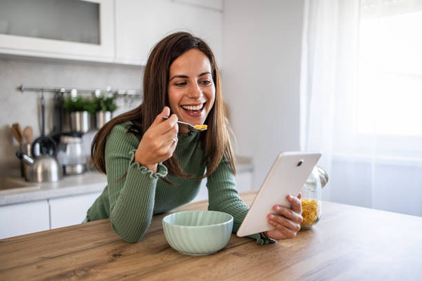 istock Happy woman enjoying breakfast and browsing social media on a tablet 2201511595