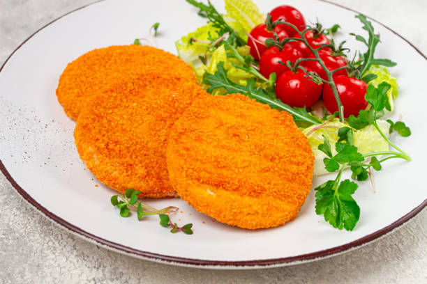 istock crispy fried fish cutlets, fish burgers, on a white plate, with fresh lettuce leaves, arugula and cherry tomatoes, homemade, no people, 2201511643