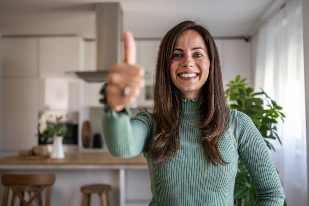 istock Smiling woman gesturing thumbs up in modern kitchen 2201514581