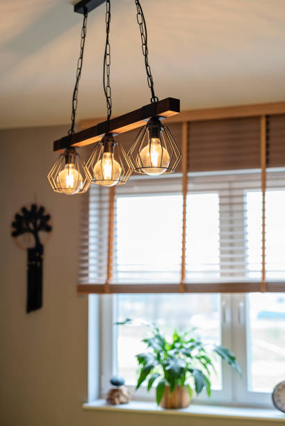istock Hanging modern lamp on the ceiling in domestic room with window and blinds. Lamp with light effect. Vertical. New apartment with stylish design. 2201516025