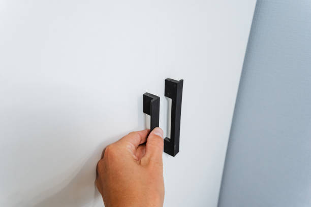 istock A person is firmly gripping a sleek, stylish black handle that is securely mounted on a clean, pristine white wall, creating an interesting visual contrast against its surroundings 2201519173
