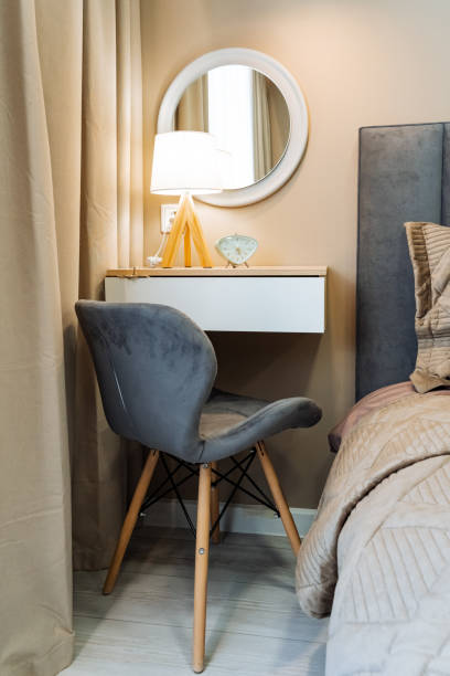 istock A contemporary modern bedroom corner that features a stylish chair, a lamp, and a mirror reflecting a beautifully cozy decor arrangement 2201519189