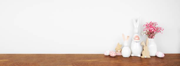 istock Modern Easter decor on a wooden shelf. Glass Easter bunnies, eggs and pink flowers. 2201521349