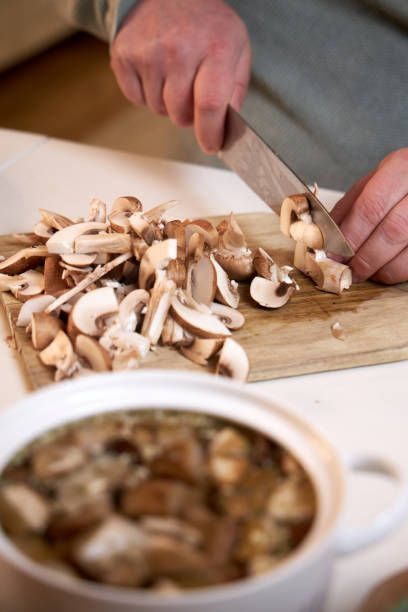 istock man cuts mushrooms on a wooden board on the kitchen table , close-up 2201523767
