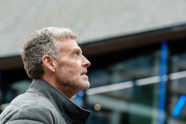 istock Pensive mature man looking up in contemplation in urban setting 2201525430