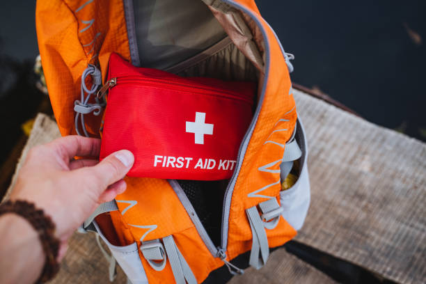 istock A person is standing with a first aid kit prominently displayed in front of a bright orange backpack, showcasing essential emergency items that are crucial for safety and preparedness 2201525633