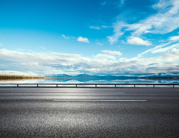 istock Asphalt road near water in summer 2201526092