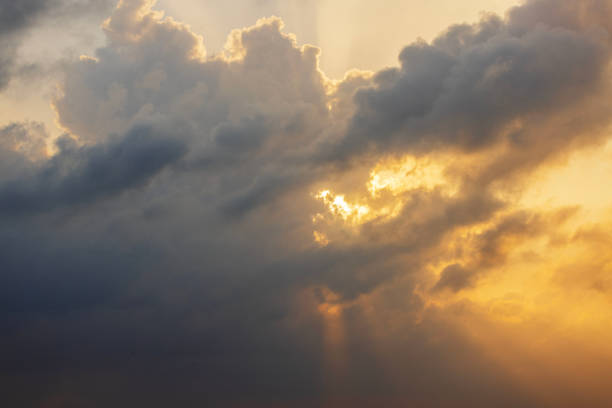 Dramatic sky with dark clouds illuminated by golden sunlight during sunset over the Caribbean Sea. Mexico.