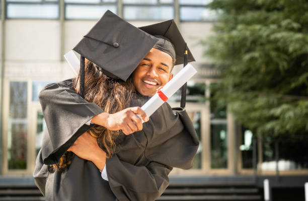 istock Happy students hugging and showing diploma after graduation ceremony 2201532653