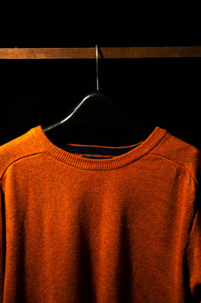 istock Front View of Plain Orange Sweatshirt on Hanger, Isolated on Black Background 2201541374
