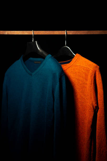 istock Plain Orange And Teal Sweatshirts on Hanger, Isolated on Black Background 2201542650