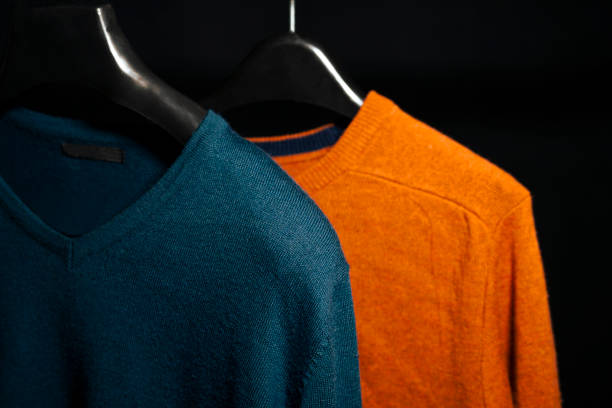 istock Plain Orange and Navy Blue Sweatshirts On hanger Isolated on Black Background 2201542651