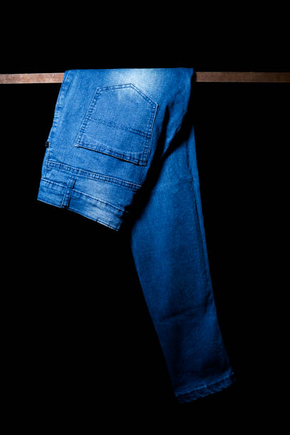 istock Blue Jeans hanging Isolated on Black Background 2201543616