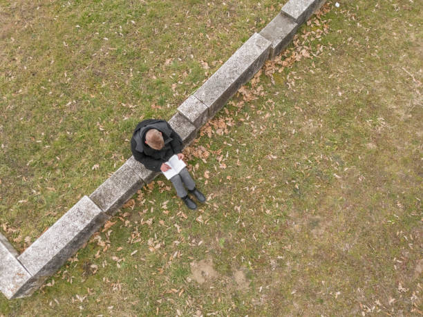 Adult man reading book outdoors in public park