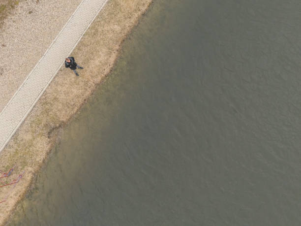 Adult man  standing and contemplate by the lake in public park