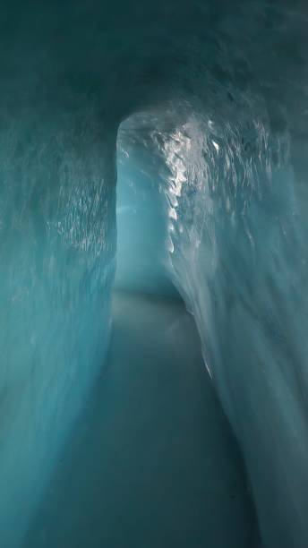 istock A narrow ice tunnel with smooth, reflective walls and a bluish glow. The passage appears deep within a glacier, creating a surreal and frozen atmosphere. Light softly illuminates the icy path ahead. 2201558130