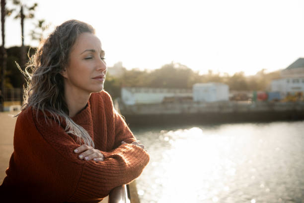istock Woman leaning on railing by river contemplating at sunset 2201570360