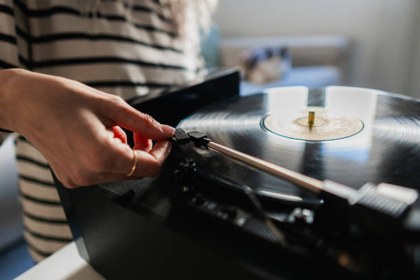 Woman carefully placing needle on vinyl record player