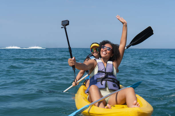 Two cheerful tourists kayaking and taking a selfie with action camera
