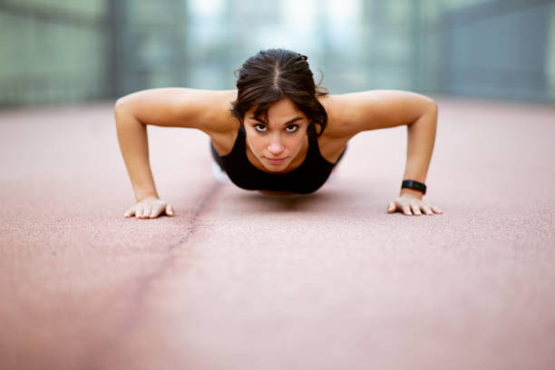 istock Strong young woman doing push ups outdoors 2201572372