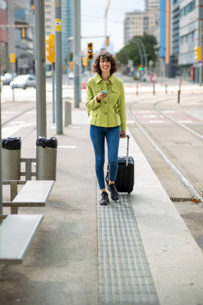 istock Woman walking with suitcase bag while using mobile phone in city 2201572968