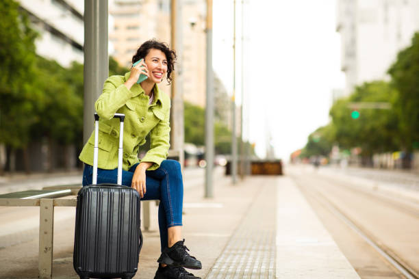 istock Happy woman talking on mobile phone while waiting at bus stop 2201572978