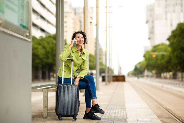 istock Smiling woman talking on mobile phone while waiting at bus stop 2201572985