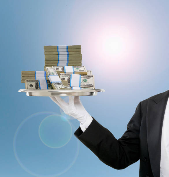Conceptual image of butler holding stack of American dollars on serving tray