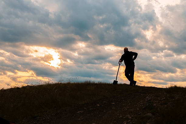 Young adult man playing guitar at mountain peak at sunset