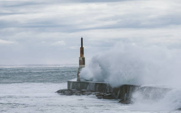 Huge waves crashing over Breakwater during winter storm Atlantic waves washing the lighthouse on Praia da Aguda sandy beach at Aguda settlement near Porto, Portugal.