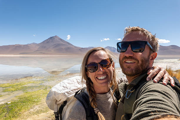 istock Happy couple taking a selfie at a serene mountain lake 2201594678