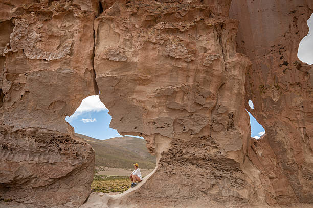 istock Woman Sitting on Eroded Rock Formation in Desert 2201595343