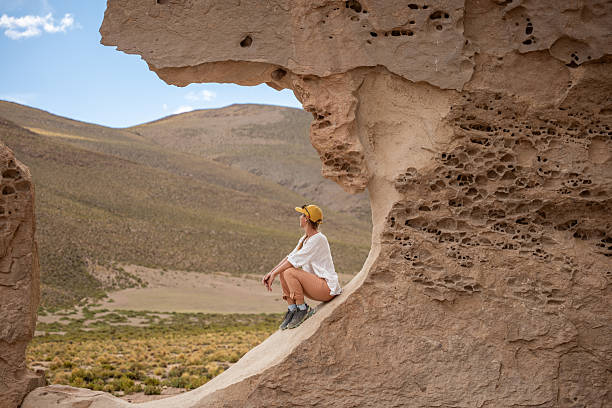 istock Woman Sitting on Eroded Rock Formation in Desert 2201595346