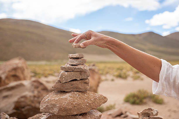 istock Hand Stacking Stones to Build a Cairn in Desert Landscape 2201595373