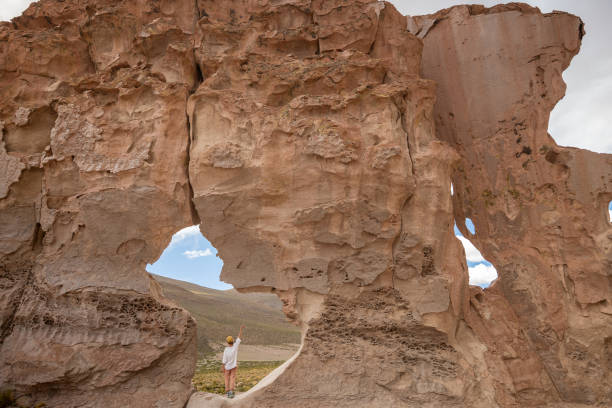 istock Traveler Standing Beneath a Massive Natural Rock Arch 2201596581