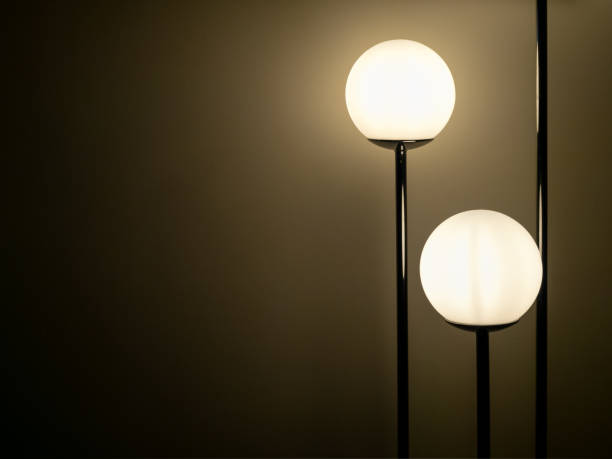istock Two round standing lamp, modern lighting balls, full moon shape with warm light shining in white wall background in the dark room with copy space. 2201598755