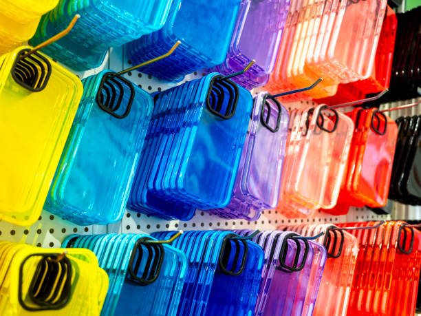 Transparent multicolor of back covers for smartphone. Colorful fluorescent mobile phone case with empty space for camera lens, hanging on hooks on shelf, white wall in the mobile accessories shop.